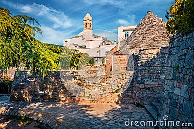 Morning view of strret with trullo trulli - traditional Apulian dry stone hut with a conical roof. Spring cityscape of Alberobe Stock Photo