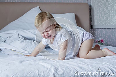 Baby screaming and crying in bed. Tantrums and whims of children. Stock Photo