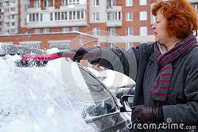 A woman cleans snow from the car Stock Photo