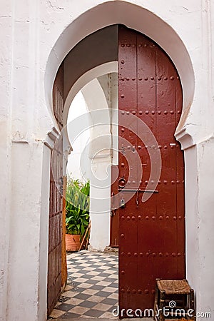 Oriental door. Old moroccan red painted wooden door with oriental frame leading to patio and garden.. Stock Photo