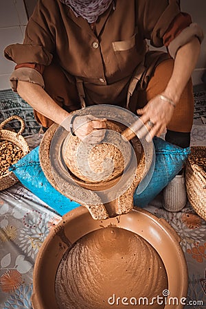 Moroccan woman grinding argan kernels into thick brown oily liquid. Stock Photo