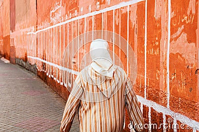 Moroccan woman seen from the back dressed in typical white and red djellaba Stock Photo