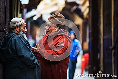 Friend senior people man talk in ancient market of Fes Medina with traditional colorful muslin dress and life style, Fes, Morocco Editorial Stock Photo