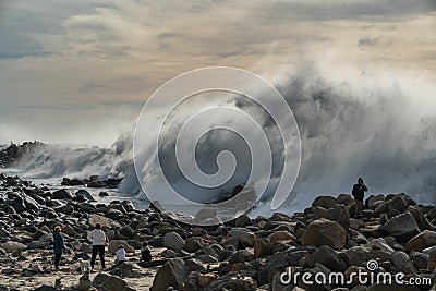 Stormy ocean waves splashing high into the air and people enjoying the view Editorial Stock Photo