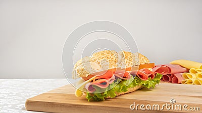 Mortadella sandwich, lettuce, tomato and cheese on a polished board and slices of mortadella and cheese next to it on a cold board Stock Photo