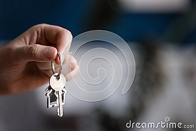 Mortgage concept. Men hand holding key with house shaped keychain. Modern light lobby interior. Real estate, moving home Stock Photo