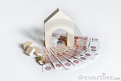 Mortgage concept. Property investment concept. House made of wooden bricks and padlock and key on a pile of Russian banknotes Stock Photo