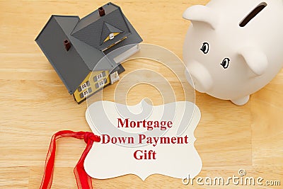 Mortgage down payment gift message on a gift tag with a model house with a piggy bank Stock Photo