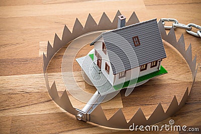 Mortgage house in a trap on wooden table background. House trap on debt or loan problem or risk in real estate property financing Stock Photo