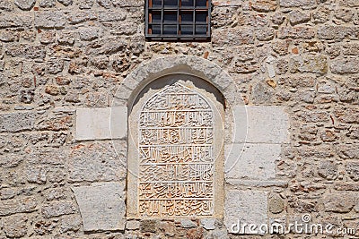 mortgaged window in the mosque. Window with inscriptions. A wall of limestone and cement Stock Photo