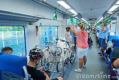 MOSCOW, AUG.29, 2018: View on seating and standing people and bikes in a special parking holder in new modern passenger train salo Editorial Stock Photo
