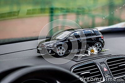 Moscow. Autumn 2018. Black toy car stays on dashboard of the same real car. Volkswagen golf 6, logo mat vw Editorial Stock Photo