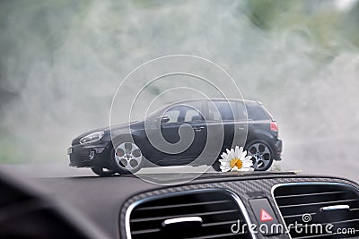 Moscow. Autumn 2018. Black toy car stays in smoke on dashboard of the same real car. Volkswagen golf 6, logo mat vw Editorial Stock Photo