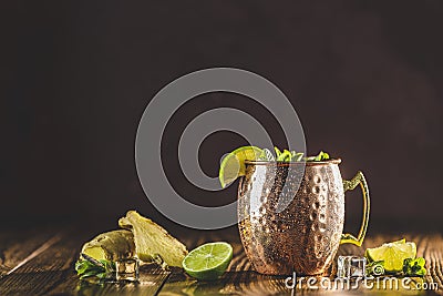 Moscow mule alcoholic cocktail in copper mug with crushed ice, mint and lemon over minton dark wooden table with amazing backlight Stock Photo