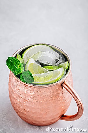 Moscow mule ice cold cocktail in copper cup with lime and and mint on gray stone background Stock Photo