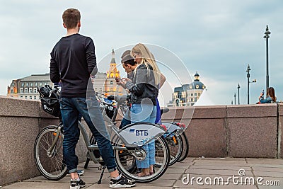 MOSCOW, RUSSIA - APRIL 30, 2018: A group of guys and girls stand with bicycles on the Moskvoretsky bridge. Bicycles for rent. Editorial Stock Photo