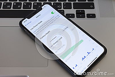 MOSCOW / RUSSIA - APRIL 4, 2020: iPhone 11 Pro lies on a MacBook keyboard. On the menu screen for setting the battery saver mode. Editorial Stock Photo