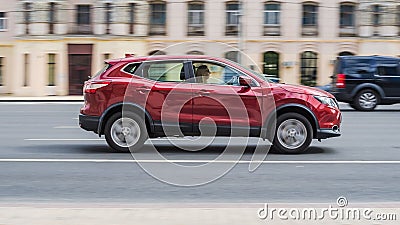 compact SUV car Nissan Qashqai in fast motion on street. Side view of red crossover automobile driving on high speed Editorial Stock Photo