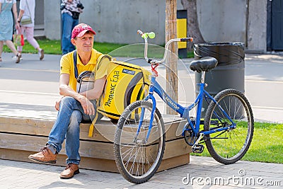 Cyclist resting next to a bicycle on a city street. The inscription in Russian Editorial Stock Photo