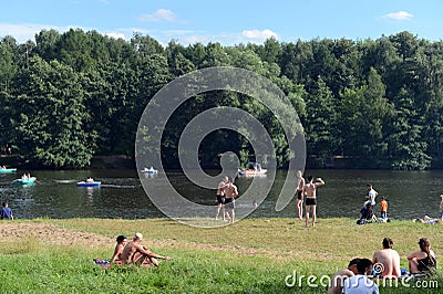 People rest on the shore of a pond in the natural-historical park `Kuzminki-Lublino` Editorial Stock Photo