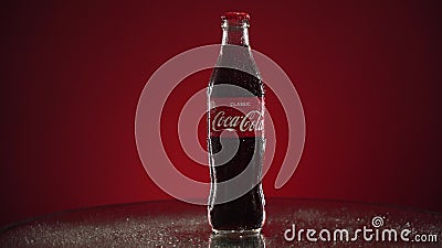 Moscow, Russia - 14 04 2020: Bottle glass of classic Coca-Cola rotate on mirrored table red background. Nice footage of Editorial Stock Photo
