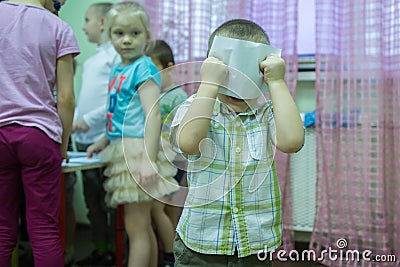 A boy holding his ready picture behind face. Editorial Stock Photo