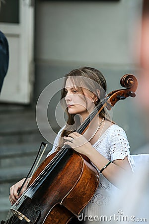 Cellist woman playing on the street, side view. Editorial Stock Photo