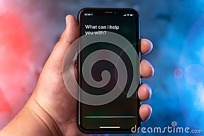 Moscow, Russia - Circa August 2019 : Siri - Apple digital assistant activated by voice in hand and text: What can I help you with? Editorial Stock Photo