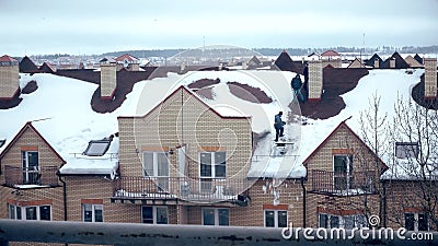 MOSCOW, RUSSIA - FEBRUARY, 20, 2017. Shoveling snow from the sloped roof after heavy snowfall Editorial Stock Photo