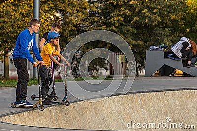 Group of teenager boys skateboarding and scooter riding in the park. Editorial Stock Photo