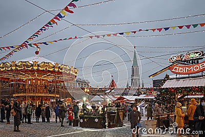 Christmas Fair Gum Fair on Red Square. People ride on a carousel in the form of a teapot and mugs. Evening, dusk Editorial Stock Photo