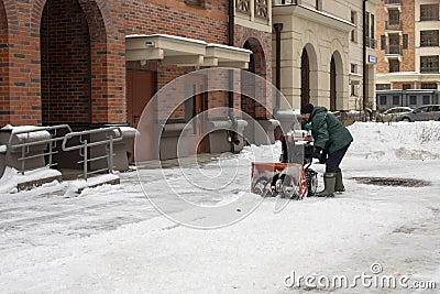 Moscow, Russia - January 4, 2021: A man clearing snow with a special snow blower. Starting the engine of the snow cleaner Editorial Stock Photo