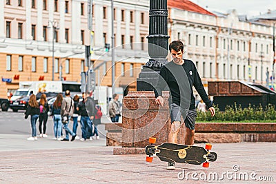 Moscow, Russia - JULY 7, 2017: young skateboarder in shorts doing a jumping trick against a crowd crossing a road Editorial Stock Photo