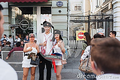 MOSCOW, RUSSIA - JUNE 2018: Polish football fan is photographed with Russian girls wearing hats in the center of Moscow Editorial Stock Photo