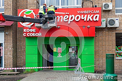 MOSCOW, RUSSIA - June 11, 2018: Workers dismantle a sign at the popular food store Pyaterochka. Editorial Stock Photo