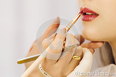 Moscow Russia - 11 13 2018: Makeup artist apply the lipstick by brush on lips of an young woman. Beauty make up Stock Photo