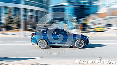 Blue BMW X6 G06 xDrive30d M Sport fast speed drive on city road Editorial Stock Photo