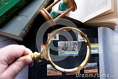 Hobby - stamp collecting. 60 cent stamp with locomotiv through a golden magnifying glass. Old books, Editorial Stock Photo