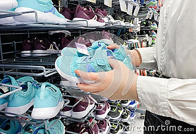 Moscow, Russia, March 2022: Someone chooses childrens or womens blue sneakers in the sports goods store Decathlon Editorial Stock Photo