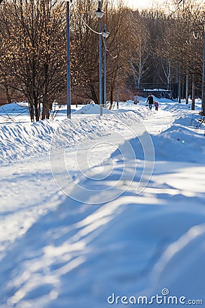 MOSCOW, RUSSIA - MARCH 20, 2018: A woman is walking with a small child on a snow-covered park alley illuminated by the sun rays Editorial Stock Photo