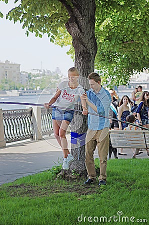 Man helps young woman in balancing during her tightrope walk in park Gorkogo in Moscow Editorial Stock Photo