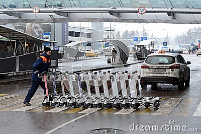 A worker pushes Luggage carts at Moscow`s Sheremetyevo international airport Editorial Stock Photo