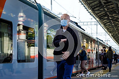 Moscow. Russia. October 4, 2020. A lone bald man in a protective medical mask and headphones walks along railway Editorial Stock Photo