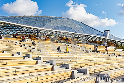 Moscow, Russia - October 08, 2019: Visitors of Zaryadye Park in Moscow resting on the wooden benches near Large amphitheatre Editorial Stock Photo