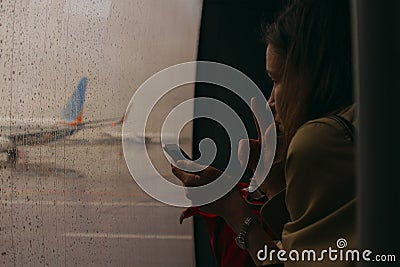 Moscow, Russia - 06 October, 2017: A young woman looks thoughtfully through a window covered in raindrops. Editorial Stock Photo