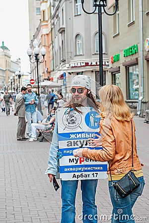 Moscow, Russia, 2015.07.09 A street advertiser is talking to a woman. Advertisement for the Aquarium History Museum on a Editorial Stock Photo