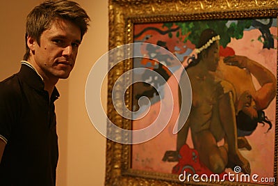 A young man standing by the picture of Gauguin `Are you Jealous?` in the art gallery of the Pushkin Museum of Fine Arts. Editorial Stock Photo