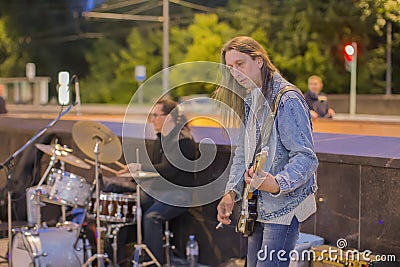 The central street of the city. Street musicians perform. A man with a guitar and a guy playing drums Editorial Stock Photo