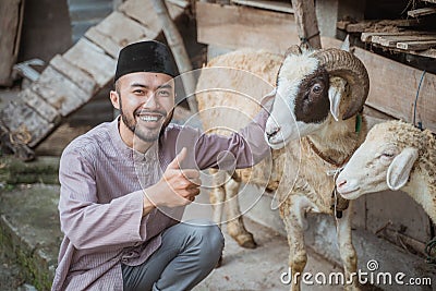 a moslem man squatting in front of the goat& x27;s stable Stock Photo