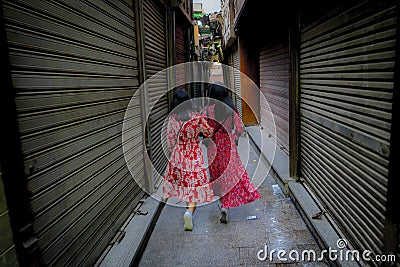 Moslem People of Egypt go shopping at Luxor Souq - two women wear bright red dresses from behind Editorial Stock Photo